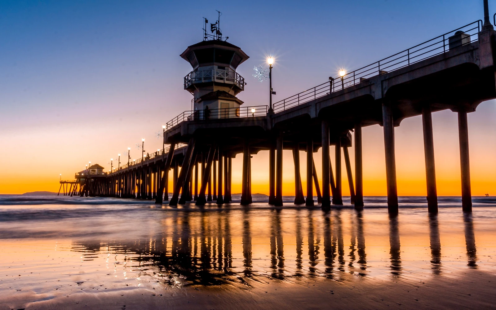 Huntington Beach Pier at sunset reflected in wet sand